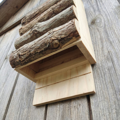 View from below into the open bottom of the bat box, showing the narrow grooved roosting crevices